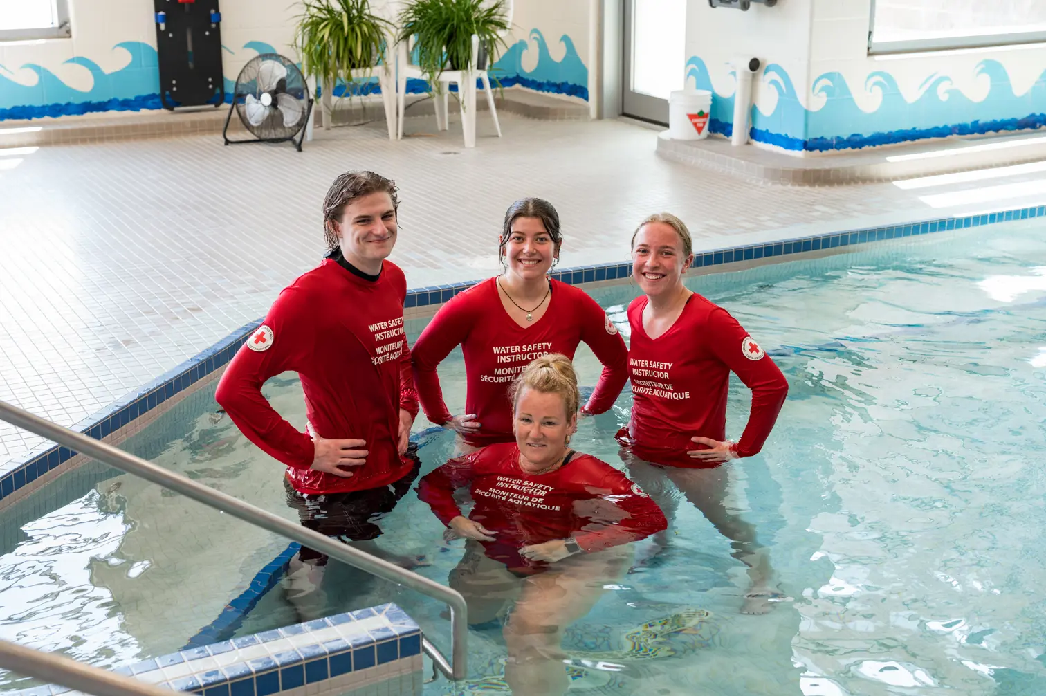 four lifeguards pose in a hot tub. Text overlay: Join the Team. 