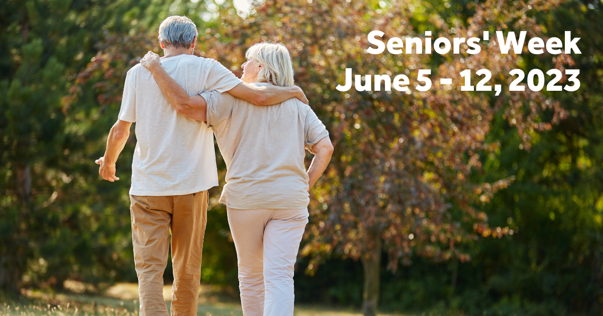 Two seniors as seen from behind walking down and outdoor pathway.