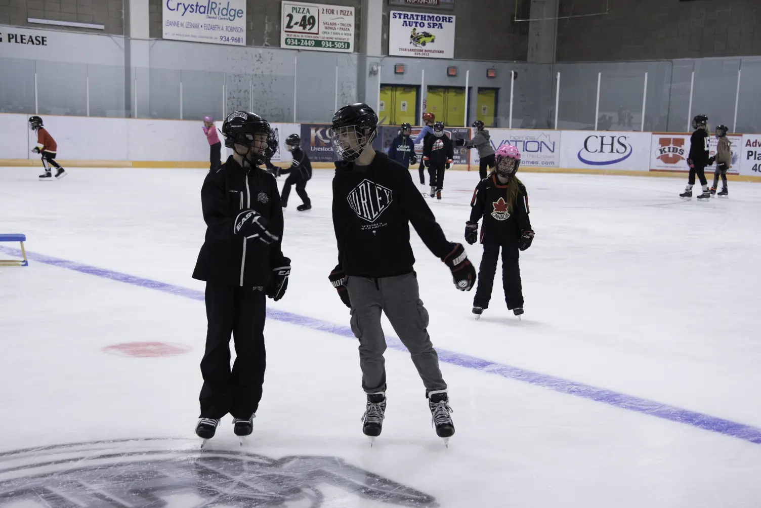 Two teens in helmets smiling on indoor ice rink. Text overlay: Teen Night