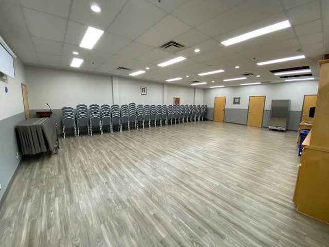 picture of an event room with chairs stacked against the wall. 