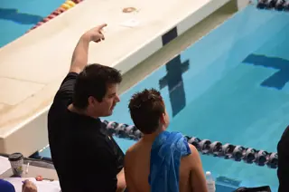 A swim instructor is coaching a male adult swimmer. Text overlay: Adult swimming lessons