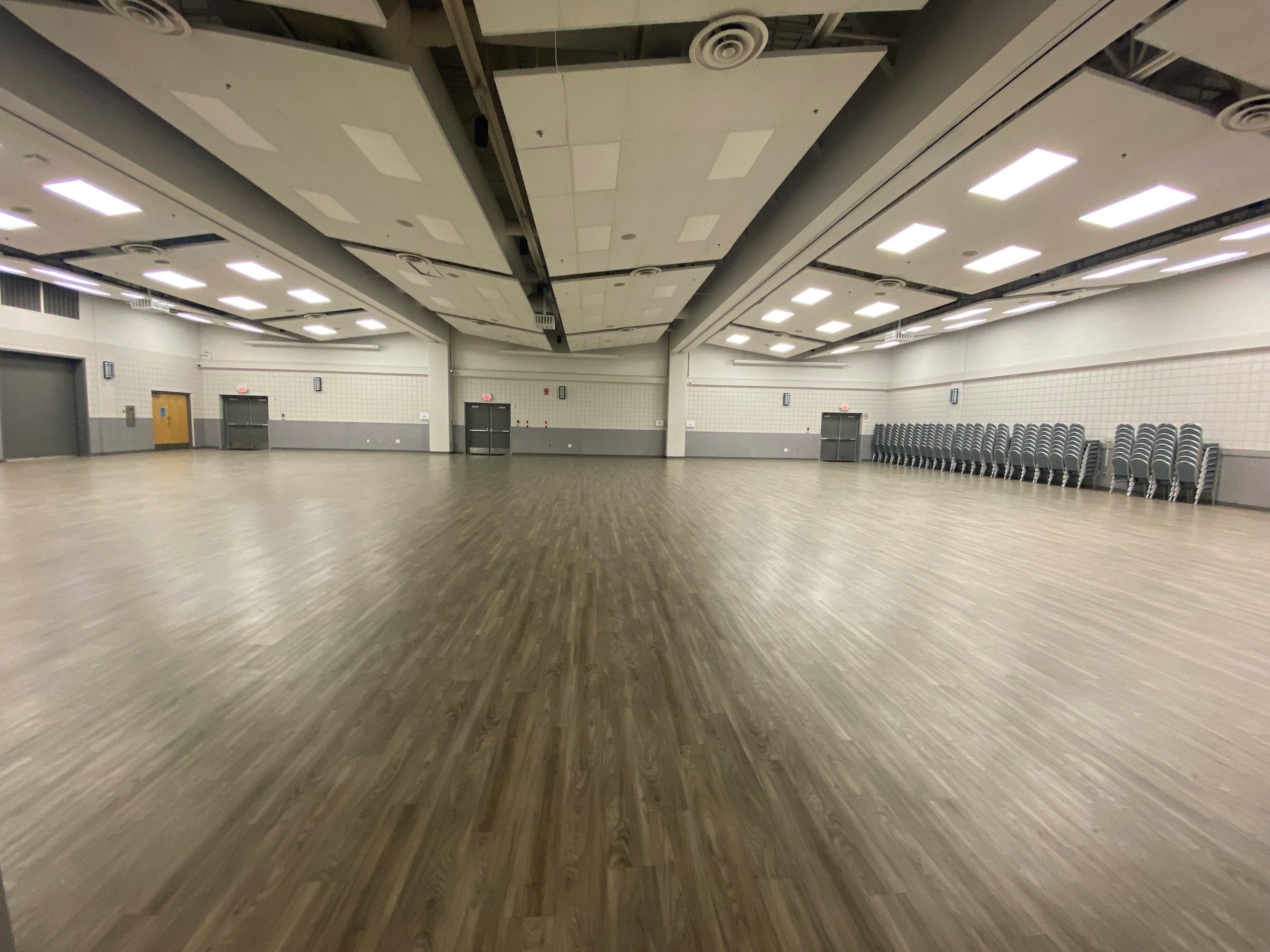picture of an event room with chairs stacked against the wall. 