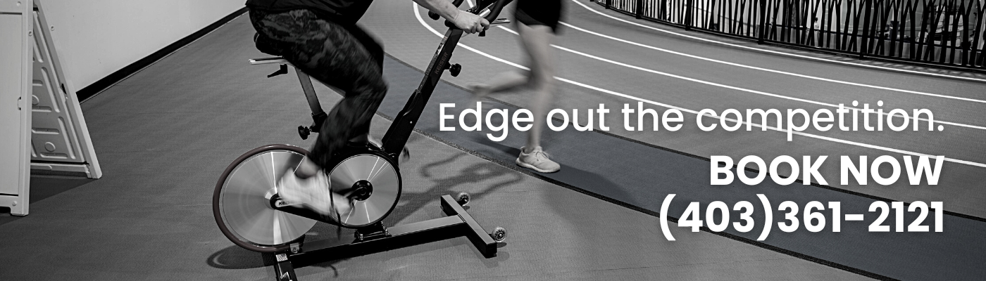 black and white picture of legs on a stationary bike while someone runs past on an indoor running track. Text overlay: Edge out the competition, book now. 403-361-2121