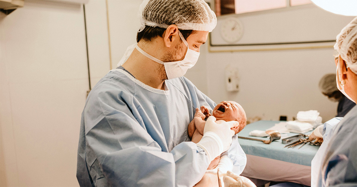 Doctor holding baby in delivery room